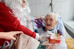 Starsza kobieta otrzymująca prezent od Mikołaja.